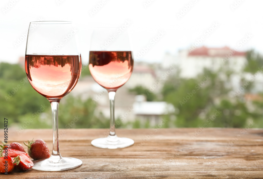 Glasses of delicious strawberry wine on blurred background