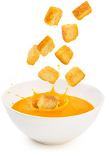 croutons falling into a soup bowl isolated on white