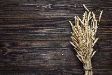 Background with ears of wheat on the dark wooden boards.