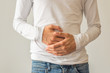 Young man holding his belly, suffering from stomach ache, diarrhea, constipation, acid reflux, indigestion, nausea