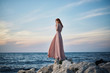 © SHOTPRIME STUDIO - A woman in a long dress is standing on stones near the sea