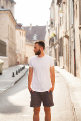 Wall Mural - Hipster handsome male model with beard wearing white blank t-shirt with space for your logo or design in casual urban style