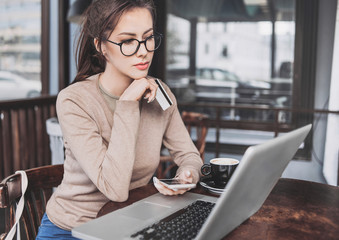 Young woman holding credit card and using laptop computer. Online shopping concept