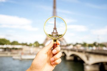 Wall Mural - Holding a magnifying glass focused on the Eiffel tower in Paris