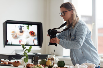 profile view of concentrated young food photographer taking picture of served table for healthy brea