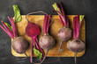 Raw organic farm beetroot on a vintage wooden cutting board on a plain black background. Top View.