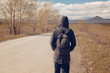 a lone man with a backpack walking along the road