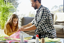 Father And Daughter Preparing Kite In Living Room
