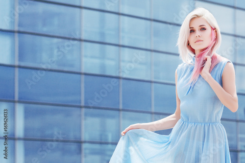 Outdoor Portrait Of Young Beautiful Girl With Makeup Long Blond Pink Hair Model Wearing Blue Dress Glass Building On Background Sunny Day Light Copy Empty Space For Text Buy This Stock