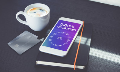 Aufkleber - Digital advertising features icons on mobile phone screen lay on black notebook with black coffee cup near window with sunlight on black wooden desk,Digital marketing strategy business concept.