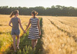 © serejkakovalev - Lovely lesbian couple together, holding hands and having good time in summer wheat fields