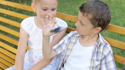 Wall Mural - Happy children sitting on the bench at the day time. They playing with spinner. Concept Brother And Sister Together Forever