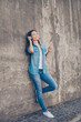 © deagreez - Enjoy the music! Young cute hipster is leaning the concrete wall in the city, listening to the music, gesturing, having fun, in modern denim outfit
