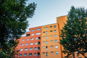 red and orange apartment building inbetween of green trees