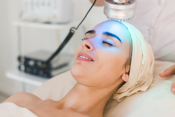 young healthy woman with good skin doing cosmetic procedures in spa clinic. light treatment.