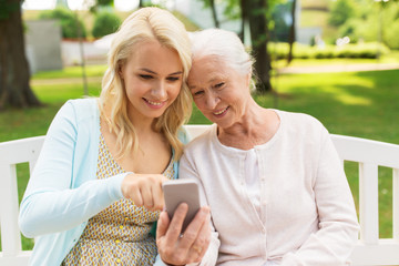 Poster - daughter and senior mother with smartphone at park