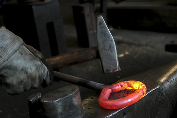 A blacksmith at work with glowing irons. Hot iron forge, a blacksmith at work with red-hot iron