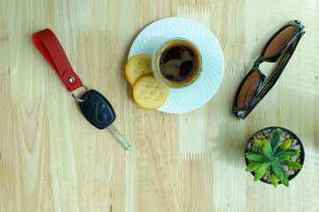 close up and top view. espresso coffee in transparent cup with two cookies and sunglasses and car key and mock up plant on the wooden table. travel, holiday concept