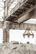 Overhead crane with mechanical multivalve clamshell grab in outdoors industrial plant shop. Heavy industry.
