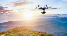 The drone with the professional camera takes pictures of the misty mountains at sunset