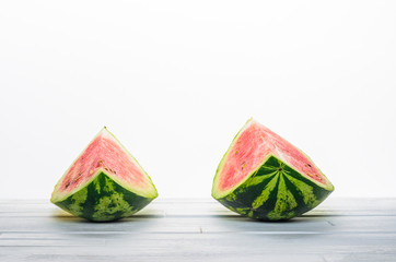 Two pieces of a watermelon on white wooden table on white background background front view. Blank minimalistic background