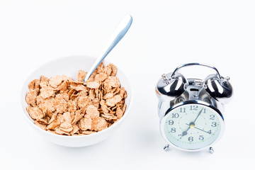 Wall Mural - useful breakfast of cereal and alarm clock on white table close-up