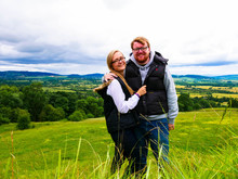 Smiling Couple In Front Of A Cotswolds Countryside Scene