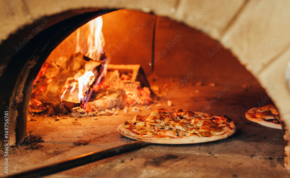 Italian pizza is cooked in a wood-fired oven. - obrazy, fototapety, plakaty 