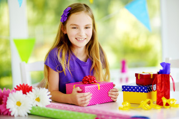 Cute preteen girl wrapping gifts in colorful wrapping paper.