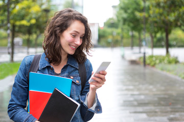 Portrait of a young student with backpack going to school and using her smartphone - Technology and education concept