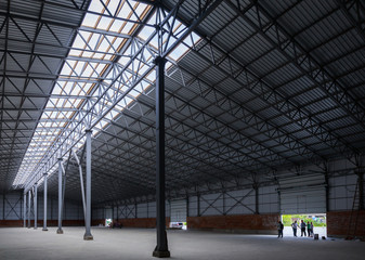 A huge metal construction warehouse. Grain dryer and threshing floor. Blurred-unrecognizable faces of people. Concept theme is the production of food and agricultural production.