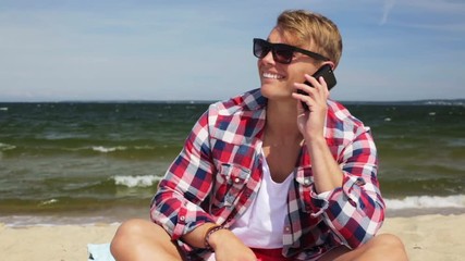 Wall Mural - smiling man calling on smartphone at summer beach