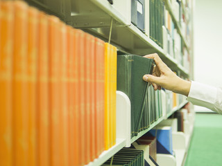 Man is selecting the book from bookshelf in a library