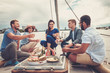 Happy friends eating fruits and drinking on a yacht