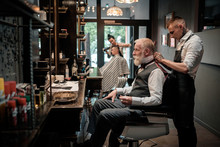 Senior Man Visiting Hairstylist In Barber Shop.