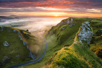 Wall Mural - long winding rural road leading into misty valley in the english peak district.