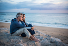 Beautiful Couple Sitting At The Beach Watching The Sunset