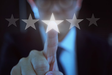 Young businessman touch the five star symbol to increase rating of company .