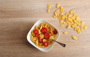 Wall Mural - cornflakes with strawberries on wooden background