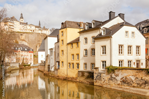 Fotografie, Obraz Alzette river running through Grund and Ville Haute above, Luxembourg city