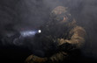 Soldier in military uniform with assault rifle aiming with laser at target in smoke on background of dark wall 19