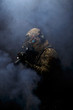 Soldier in military uniform with assault rifle aiming with laser at target in smoke on background of dark wall 15