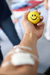 blood donor at donation with a bouncy ball holding in hand.The hand of a blood donor squeezing a medical yellow rubber smileing ball while blood donation
