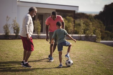 Wall Mural - Boy playing football with his father and grandson