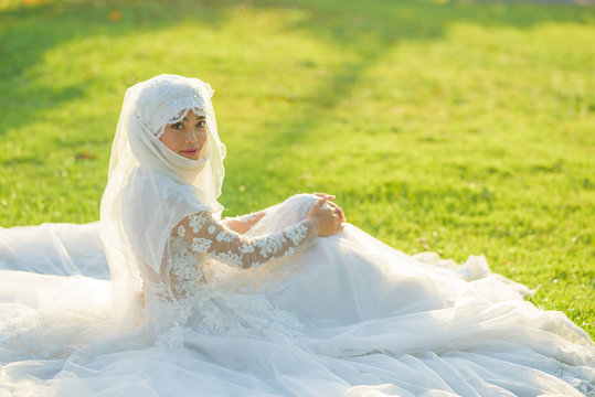 Portrait of a beautiful muslim bride with make up in white wedding dress with beautiful white headdress natural light.