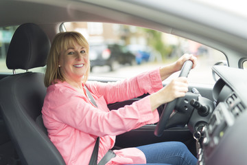 Happy and smiling senior woman in black car