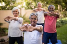 Portrait Of Senior Woman Stretching Arms With Friends