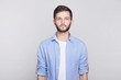 © Yulia - Portrait of Caucasian handsome brunette  guy with blue eyes, trendy hairdo and beard looking seriously at camera while posing against white studio wall. Grave businessman in shirt thinking about work.