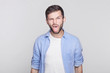 © Yulia - Emotional and bearded  young handsome brunette man employee wearing blue shirt grimacing, making mouths, sticking out his tongue at camera trying to tease someone, acting like a little naughty child.