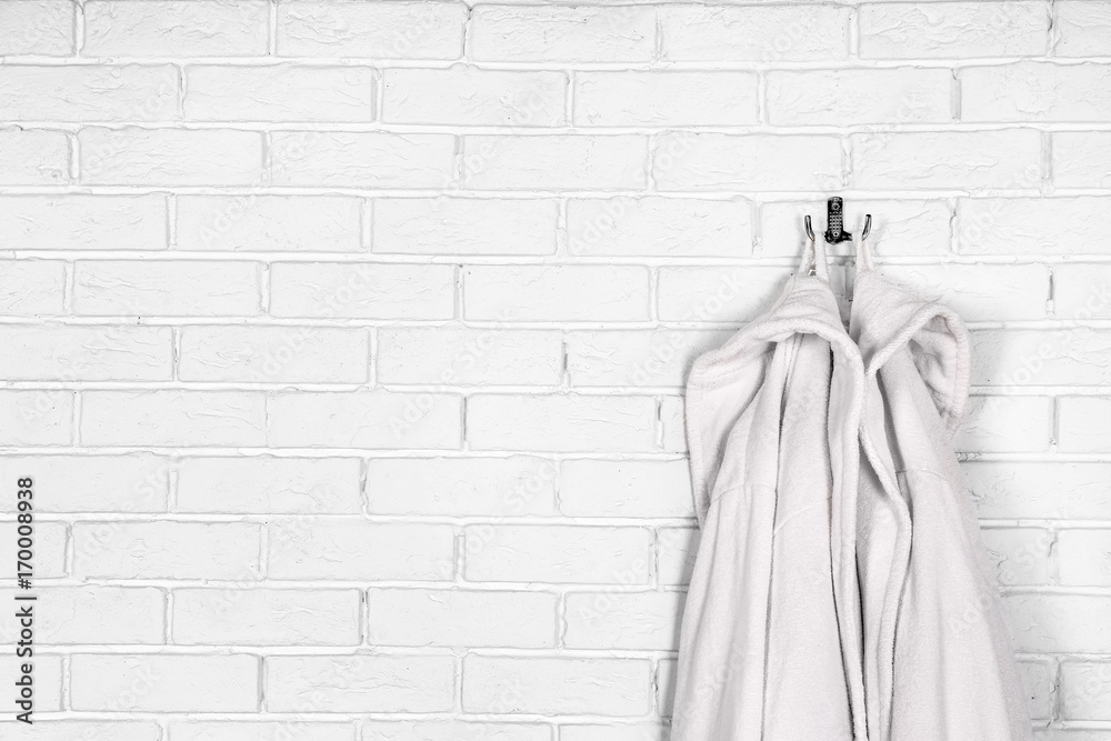Bathrobes hanging on brick wall